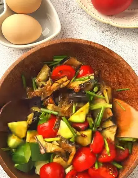 Crispy Eggplant Salad with fresh tomatoes, cucumbers, and herbs in a wooden bowl