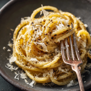 Lazy girl pasta plated with Parmesan shavings, black pepper, and a fork twirling pasta