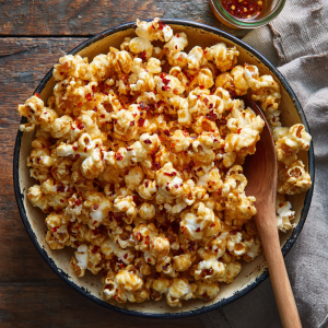 Hot honey popcorn in a rustic bowl with glossy honey-butter glaze and chili flakes